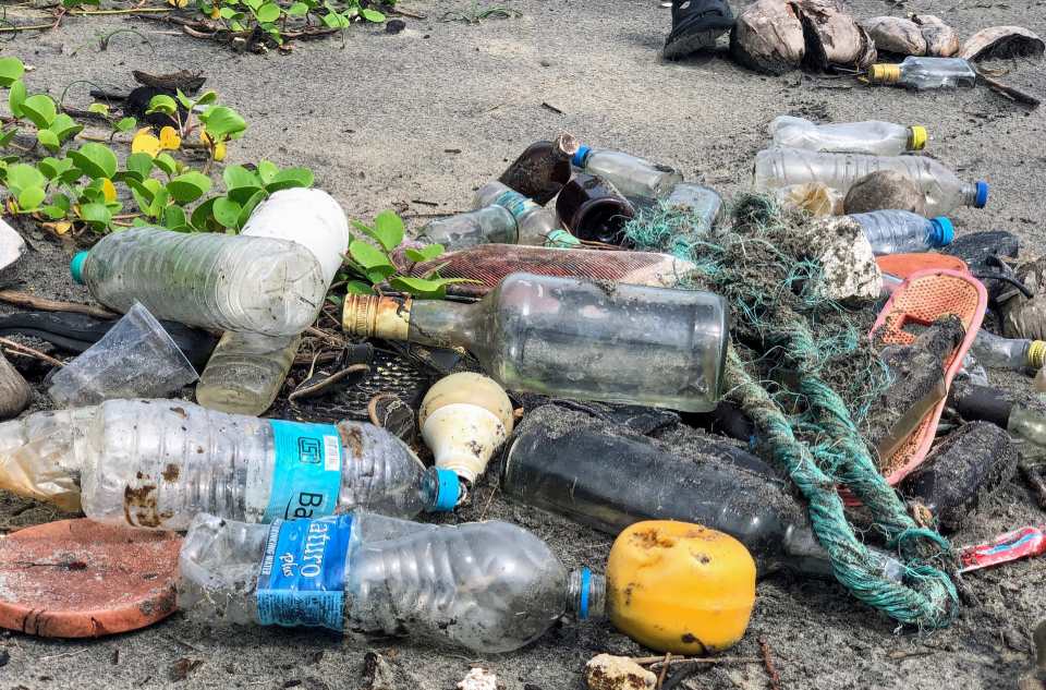 Washed up plastic bottles on a beach with other waste